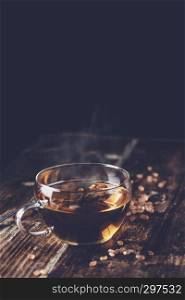 freshly poured tea with brown tea sugar on a wooden background