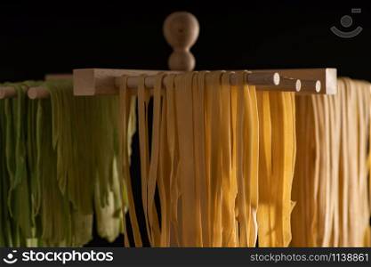 Freshly prepared Tagliatelle paste is dried on a wooden drier. Traditional italian cuisine.
