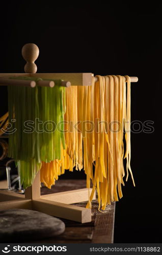 Freshly prepared Tagliatelle paste is dried on a wooden drier. Traditional italian cuisine.