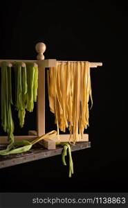 Freshly prepared Tagliatelle paste is dried on a wooden drier. Traditional italian cuisine.