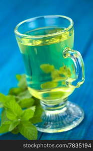 Freshly prepared tea out of the Peruvian herb called Muna (lat. Minthostachys mollis), which is a herbal and medicinal plant with a taste similar to mint, and is either prepared as tea or used as a spice in some regions (Selective Focus, Focus on the front rim of the glass)