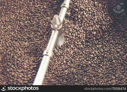 Freshly roasted aromatic coffee beans in a modern coffee roasting machine, vintage filter image