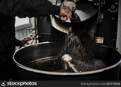 Freshly roasted coffee beans pouring from a large coffee roaster into the cooling cylinder. 