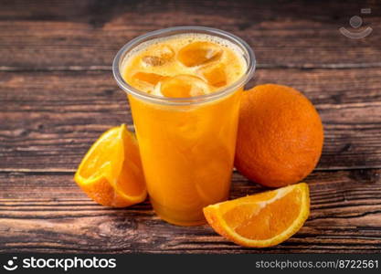 Freshly squeezed orange juice with ice cubes on wooden table
