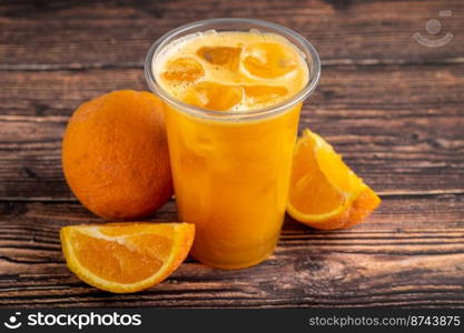 Freshly squeezed orange juice with ice cubes on wooden table