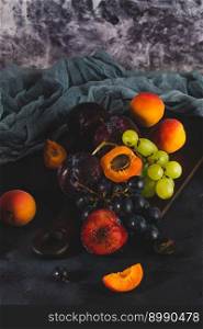 Freshly washed fruits with water droplets. bright high key look conveys freshness. Variety of fresh grapes, apricot and plumes on dark background. Fruit sources of vitamins