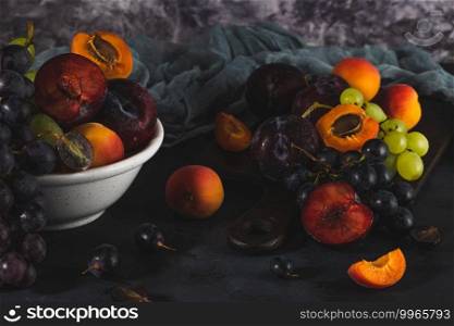 Freshly washed fruits with water droplets. bright high key look conveys freshness. Variety of fresh grapes, apricot and plumes on dark background. Fruit sources of vitamins
