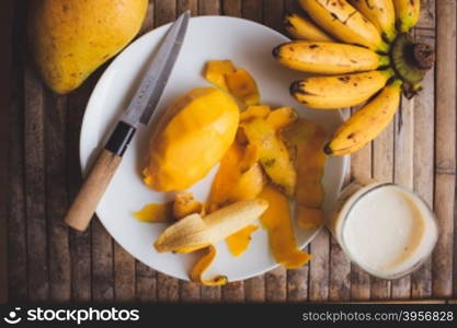 freshness fruit mango lying on a white plate with knife. Fresh shake with milk and straw on brown board rustic