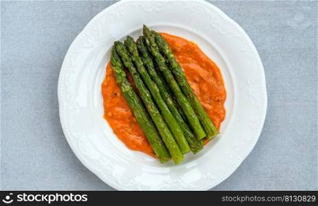 Fried asparagus with romesco sauce on white plate
