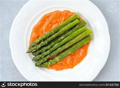 Fried asparagus with romesco sauce on white plate