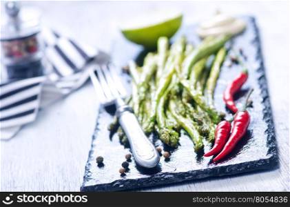 fried asparagus with spice on the black stone board