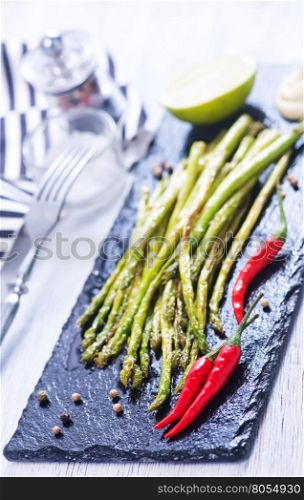 fried asparagus with spice on the black stone board