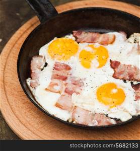 Fried bacon and eggs on the pan - rusty breakfast