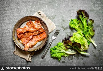 Fried bacon and greens. On a stone background.. Fried bacon and greens. On stone background.