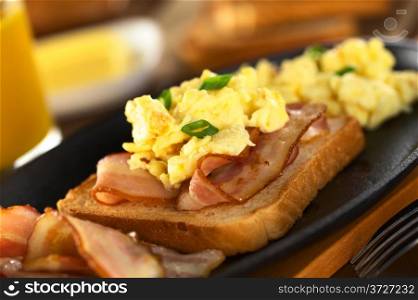 Fried bacon and scrambled egg on toast bread (Selective Focus, Focus on the front of the shallot in the front) . Bacon and Egg on Toast Bread