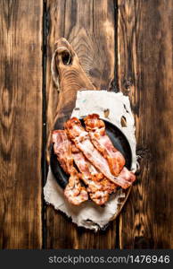 Fried bacon in a frying pan. On a wooden table.. Fried bacon in a frying pan. On wooden table.