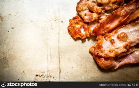 Fried bacon. On an old rustic background.. Fried bacon. On old rustic background.