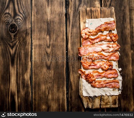 Fried bacon on the fabric. On a wooden table.. Fried bacon on the fabric.