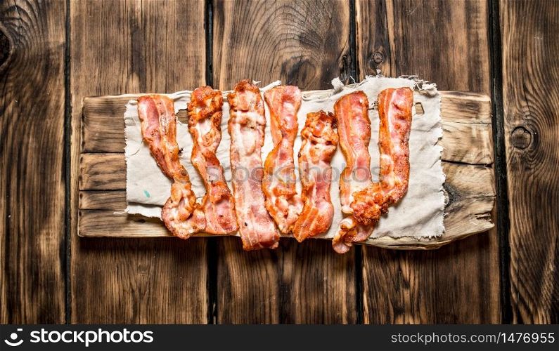 Fried bacon on the fabric. On a wooden table.. Fried bacon on the fabric.