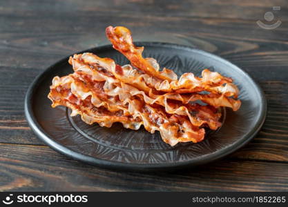 Fried bacon strips on the plate close up
