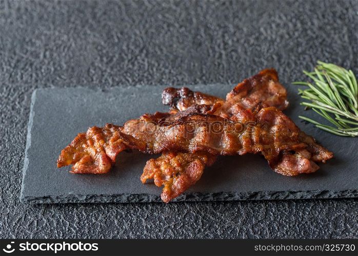 Fried bacon strips on the stone dark board