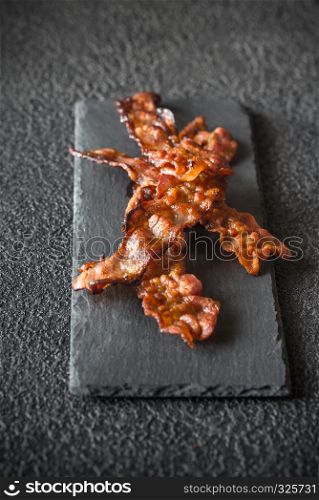 Fried bacon strips on the stone dark board