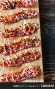 Fried bacon strips on the wooden board
