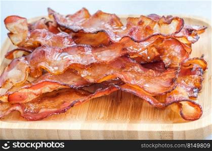Fried bacon strips on the wooden plate