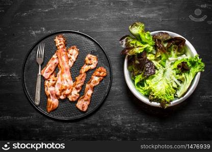 Fried bacon with greens. On a black wooden background.. Fried bacon with greens. On black wooden background.