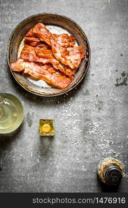 Fried bacon with oil and salt. On a stone background.. Fried bacon with oil and salt. On stone background.