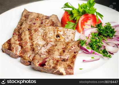 fried beef or pork liver with fresh vegetable salad served on plate. fried beef liver with vegetables