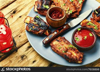 Fried beef ribs with tomato sauce on a old wooden table. Delicious fried ribs