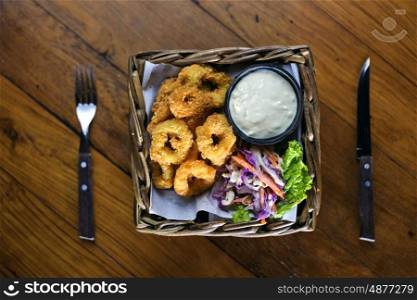 Fried calamari rings in wood basket.