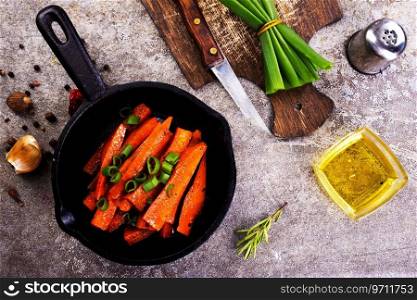 Fried carrots with green herbs in baking tray, close up