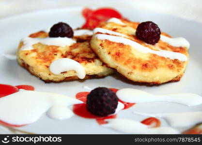 fried cheese cakes on the plate with berries of raspberry