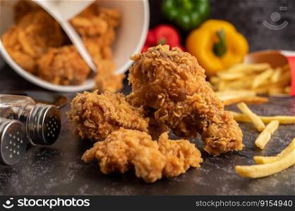 Fried Chicken and French Fries on Black Cement Floor.