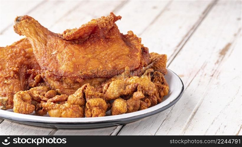 fried chicken and fried chicken skin in ceramic plate on white old wood texture background with copy space for text