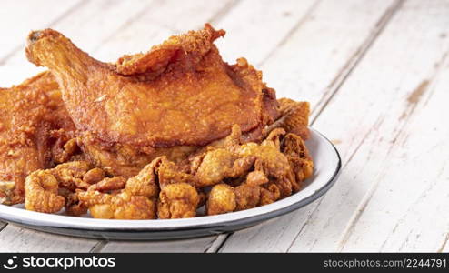 fried chicken and fried chicken skin in ceramic plate on white old wood texture background with copy space for text