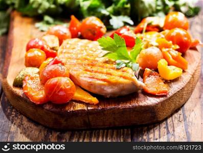 fried chicken breast with vegetables on wooden board
