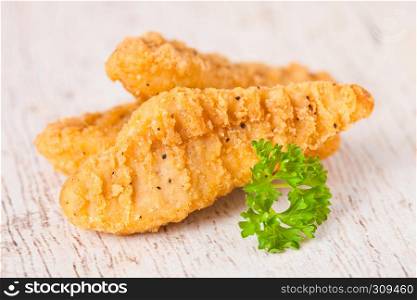Fried chicken dippers on chopping board with sauce and fresh salad on wooden background