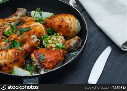 fried chicken drumsticks in a frying pan on wooden table