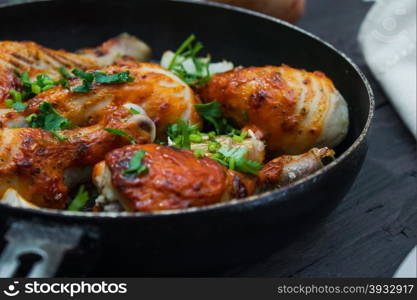 fried chicken drumsticks in a frying pan on wooden table