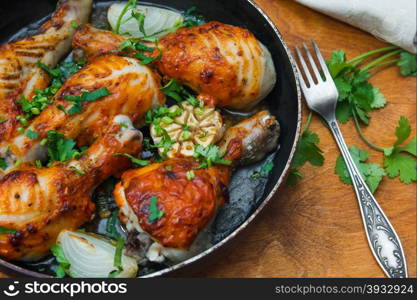 fried chicken drumsticks in a frying pan on wooden table