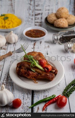 Fried chicken, fork and chili sauce in white cup with spices on a white wooden floor