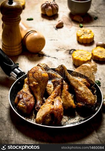 Fried chicken legs with corn and garlic. On a wooden table.. Fried chicken legs with corn and garlic.
