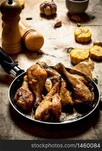 Fried chicken legs with corn and garlic. On a wooden table.. Fried chicken legs with corn and garlic.