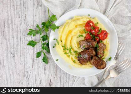 Fried chicken liver with vegetable garnish of mashed potatoes and baked cherry tomatoes, seasoned with butter