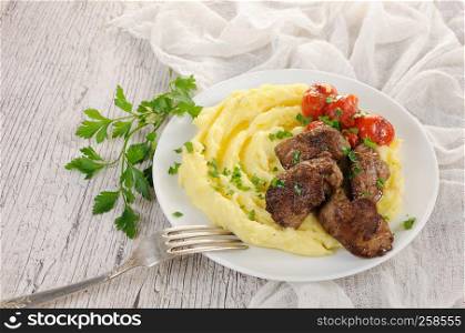 Fried chicken liver with vegetable garnish of mashed potatoes and baked cherry tomatoes, seasoned with butter