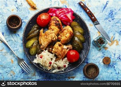 Fried chicken meat and a side dish of pickles. English cuisine.. Roasted chicken meat and pickles.