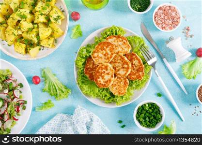 Fried chicken meat cutlets, fresh vegetable salad with radish, lettuce and cucumber, boiled new potato with butter, dill and green onion for lunch